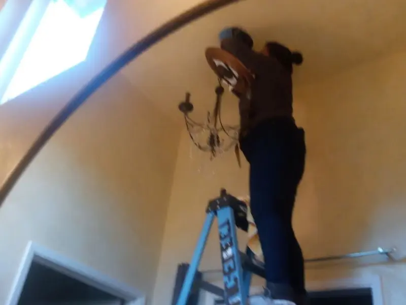 Electrician installing a chandelier in a Fate residence